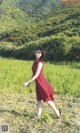 A woman in a red dress is walking through a field.