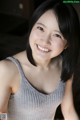 A smiling young woman in a gray tank top.