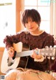 A woman sitting on a couch playing a guitar.