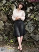 A woman standing in front of a stone wall.