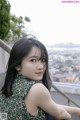 A woman in a green dress sitting on a railing.