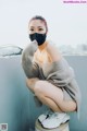 A woman wearing a face mask sitting on top of a stool.