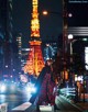 A woman standing in front of the Eiffel Tower at night.