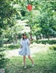 A woman in a blue dress holding a red balloon.