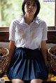 A woman in a white shirt and blue skirt sitting on a window sill.