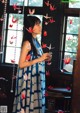 A woman standing in front of a window holding a bunch of paper cranes.